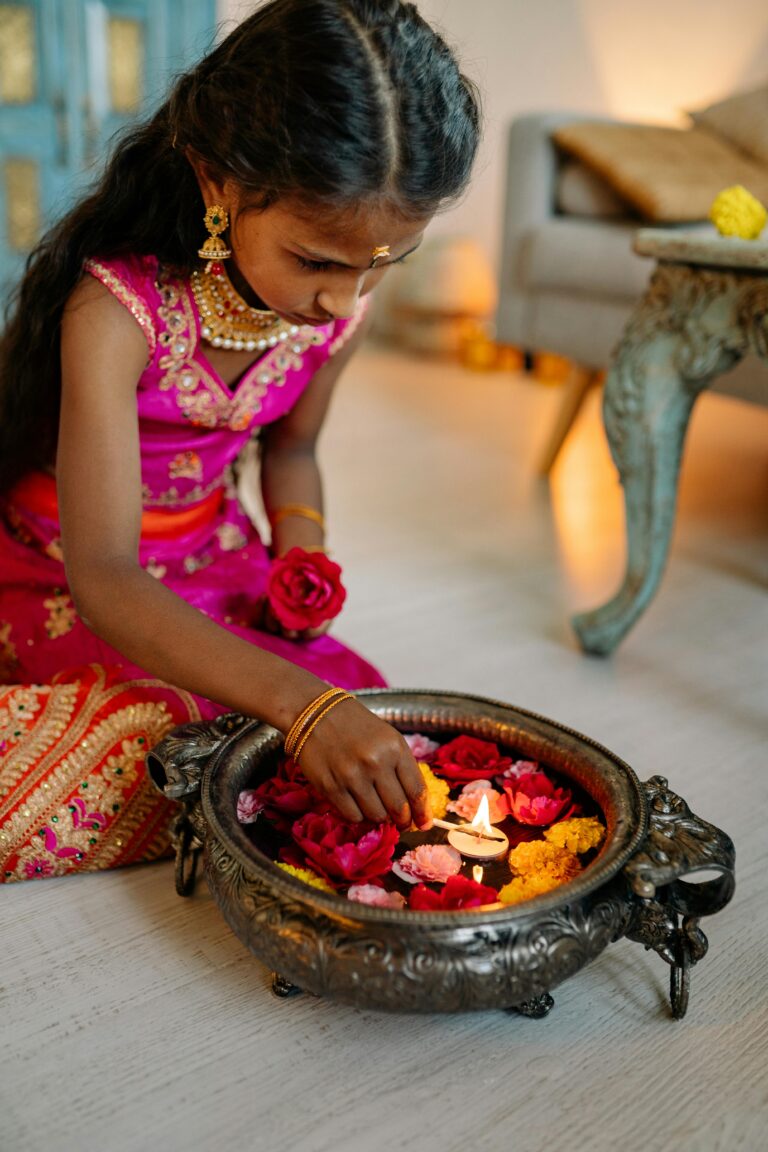 A young girl in traditional attire lights candles during Diwali, enhancing cultural celebrations.
